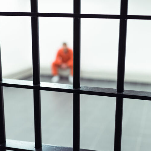 A Man Sits in a Jail Cell.