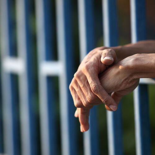 Hands Stick out of a Jail Cell.
