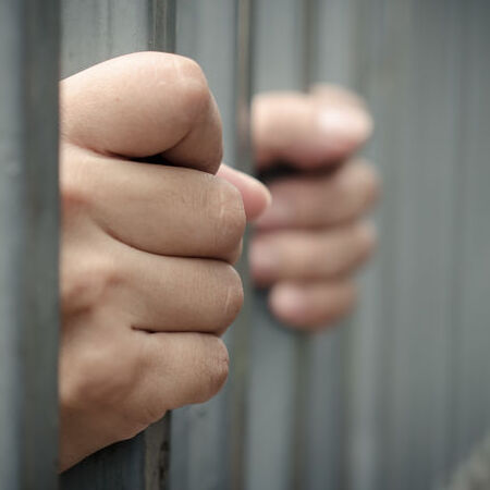 hands on bars in jail cell